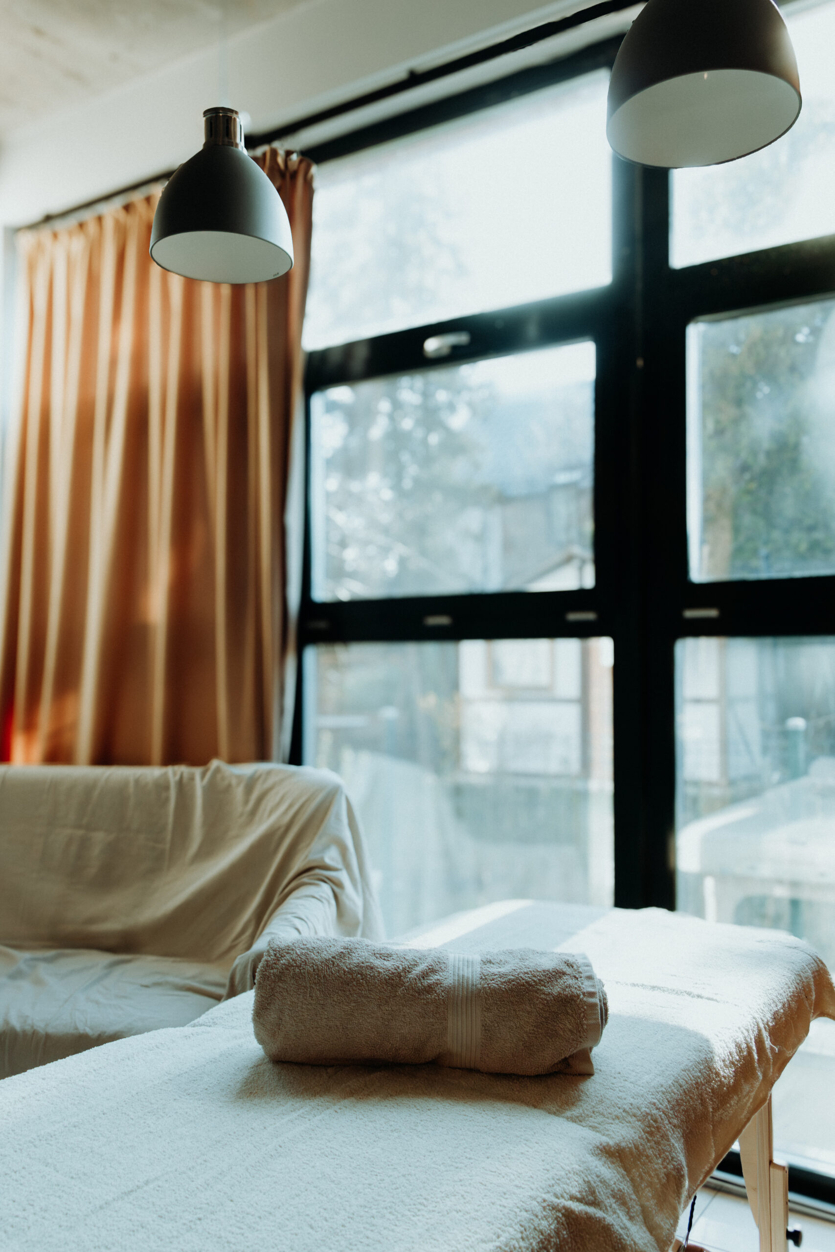 massage table, window with curtains and sofa